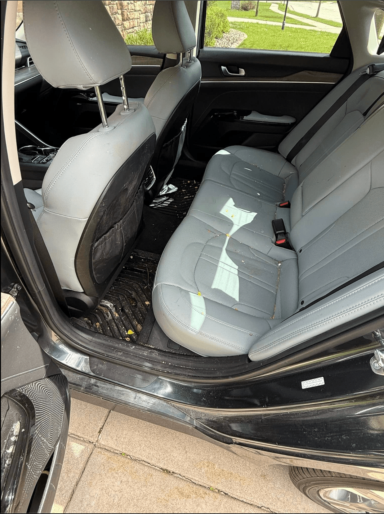 Rear seats and floor mats during cleaning, with visible water and dirt before drying